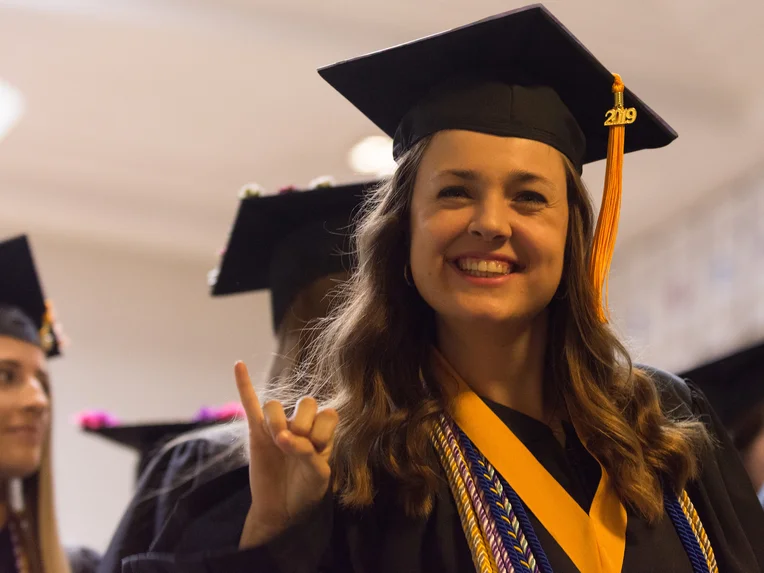 Student giving stingers up gesture at Commencement