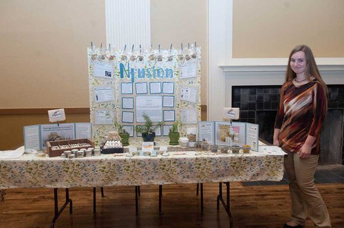 Megan Allen stands next to her booth displaying her company, Nfusion. 