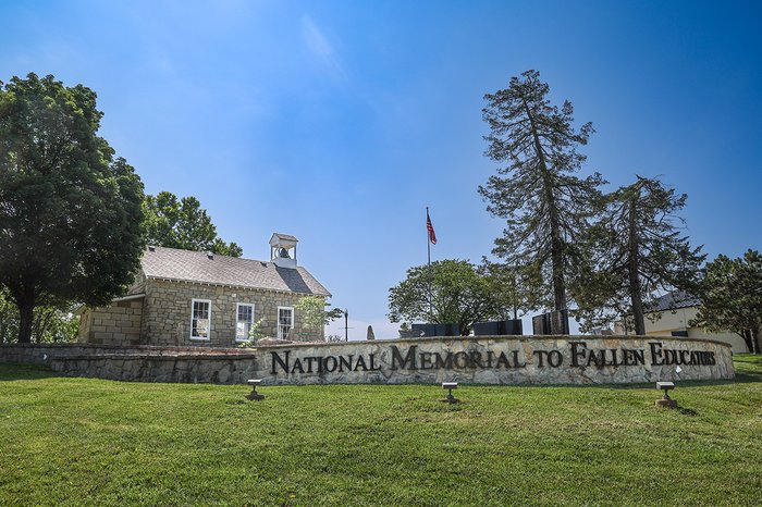 Scenic shot of National Memorial to Fallen Educators with three black granite books rising vertically above a limestone block wall.