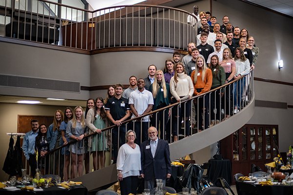 group of Emporia State University students standing on spiral staircase with two people standing on floor below