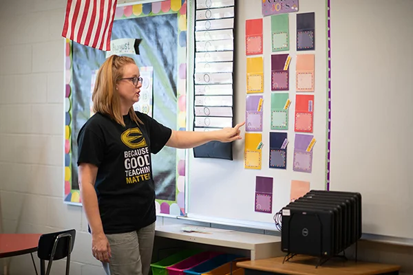 Teacher showing student jobs board in a classroom