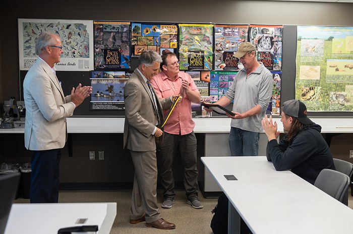 Four men look at an award