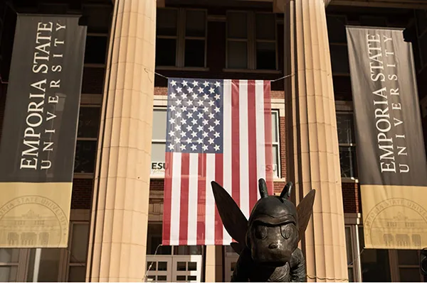 Front of brick building with banners and U.S. flag suspended between columns.