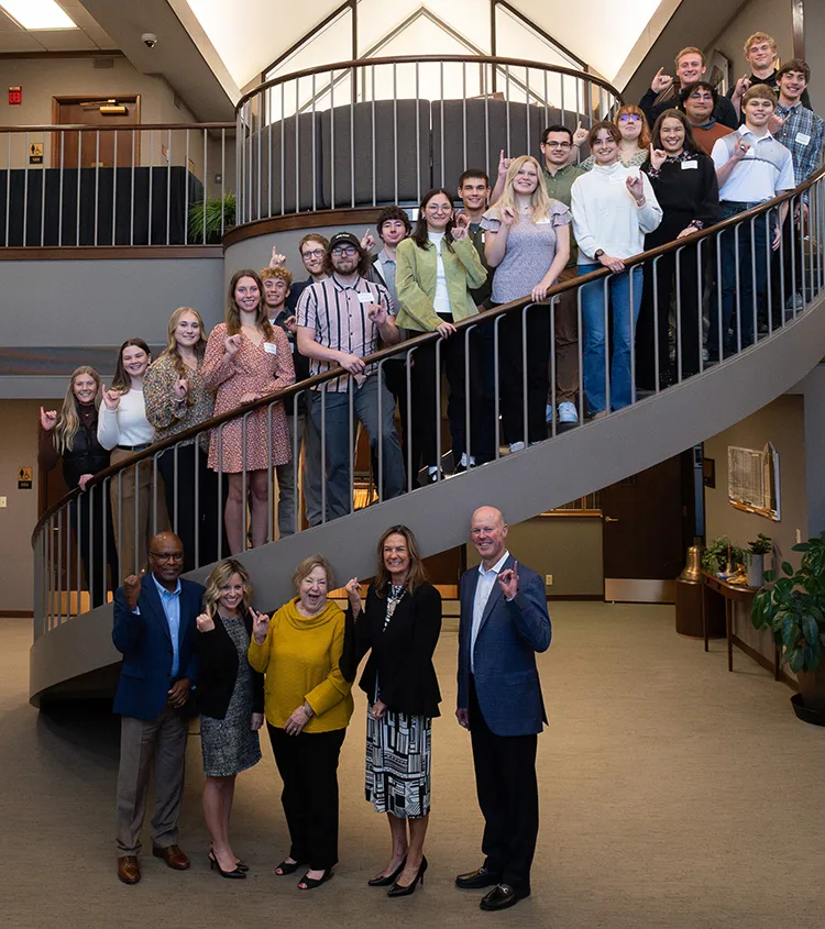 Students stand along a spiral staircase.