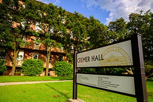 Brick building with gold sign in front that says, "Cremer Hall"