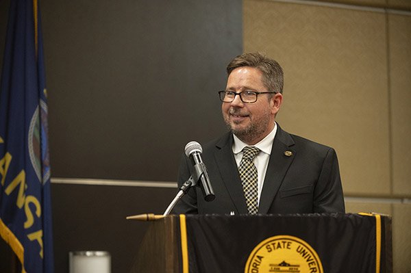 Man with beard and glasses speaks at podium