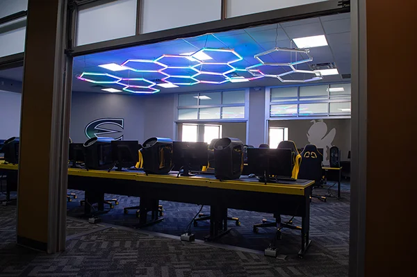 Desks, tall-backed chairs and computers sit on tables.