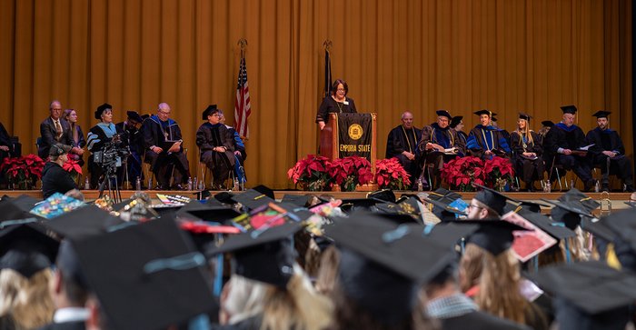 Speaker at a podium with people seated on either side.